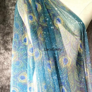 May include: Teal blue sheer fabric with a peacock feather print. The fabric has a subtle sparkle and is perfect for crafting or sewing projects.