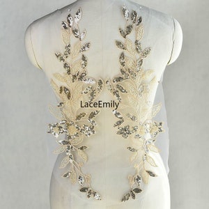 Może przedstawiać: Dwa złote aplikacje kwiatowe z cekinami i perłami na przezroczystym tle z tkaniny. LaceEmily jest nadrukowane na tkaninie.