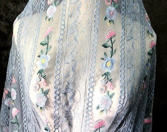 Puede incluir: Tela transparente azul claro con patrones florales bordados en rosa, blanco y verde. La tela tiene una textura delicada y de encaje.