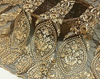 May include: Black mesh fabric with gold embroidery featuring a paisley pattern. The fabric is delicate and sheer, with a soft, flowing texture.