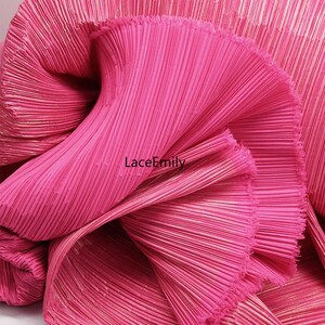 May include: Close-up of a vibrant pink pleated fabric. The fabric is tightly folded, creating a textured surface with vertical lines. The brand name "LaceEmily" is visible on the fabric.