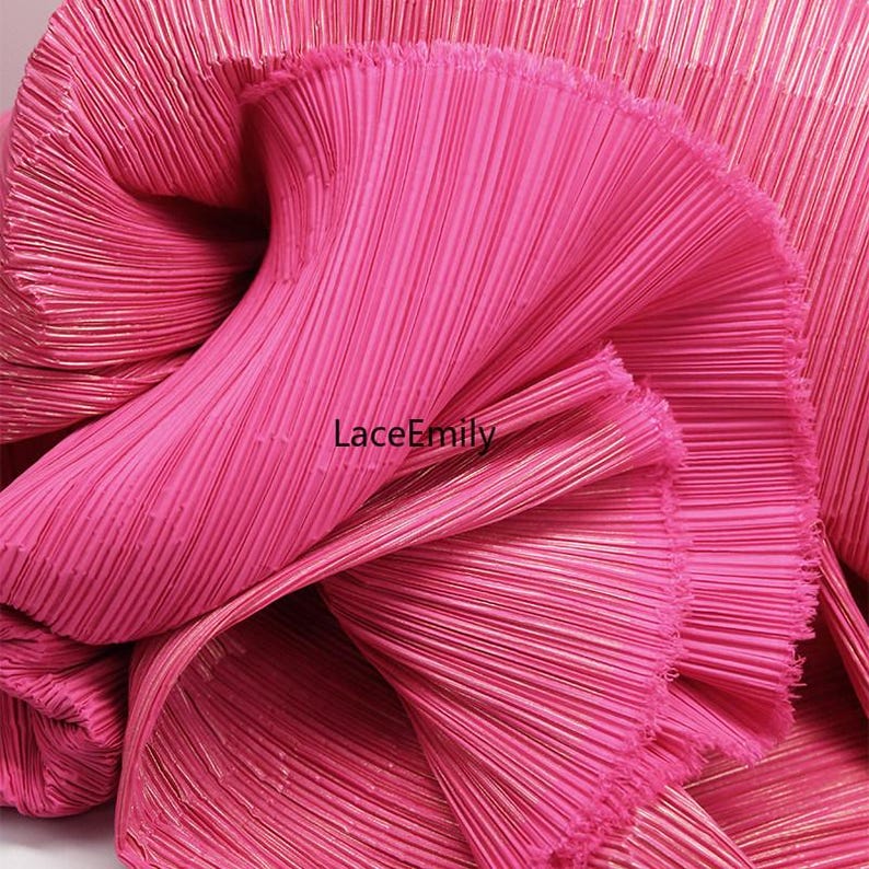 May include: Close-up of a vibrant pink pleated fabric. The fabric is tightly folded, creating a textured surface with vertical lines. The brand name "LaceEmily" is visible on the fabric.