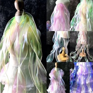 May include: A collection of iridescent sheer fabric in various colors, including green, pink, and blue. The fabric is draped over mannequins, showcasing its flowing and translucent qualities.