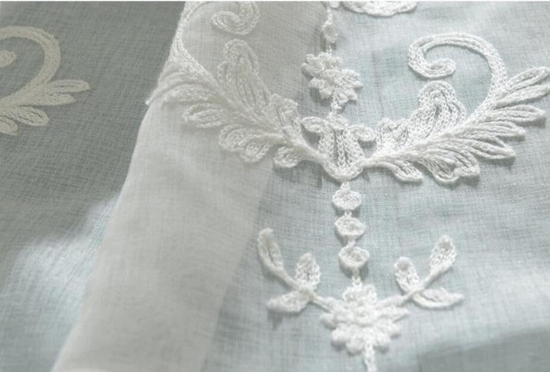 May include: White sheer curtain fabric with delicate white embroidered floral designs.