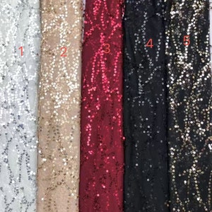 May include: Five samples of sequined fabric in different colors: silver, gold, red, black, and gold. The fabric has a mesh base with sequins in a floral pattern.