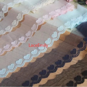 May include: Four different colors of lace trim with a scalloped edge and a heart design. The colors are black, brown, light blue, and pink.
