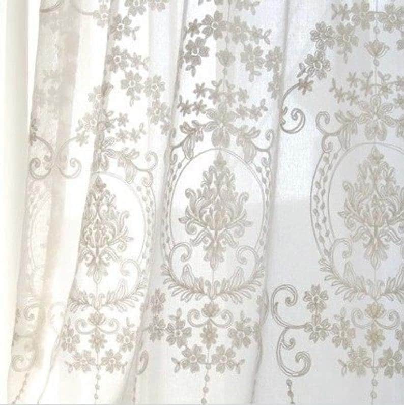 May include: White sheer curtains with an intricate embroidered floral and damask pattern.