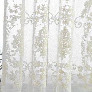May include: White sheer curtains with an embroidered floral pattern.