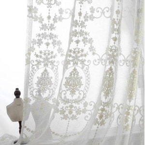 May include: White sheer curtains with an embroidered floral pattern. The curtains are made of a delicate fabric and have a romantic, vintage feel.