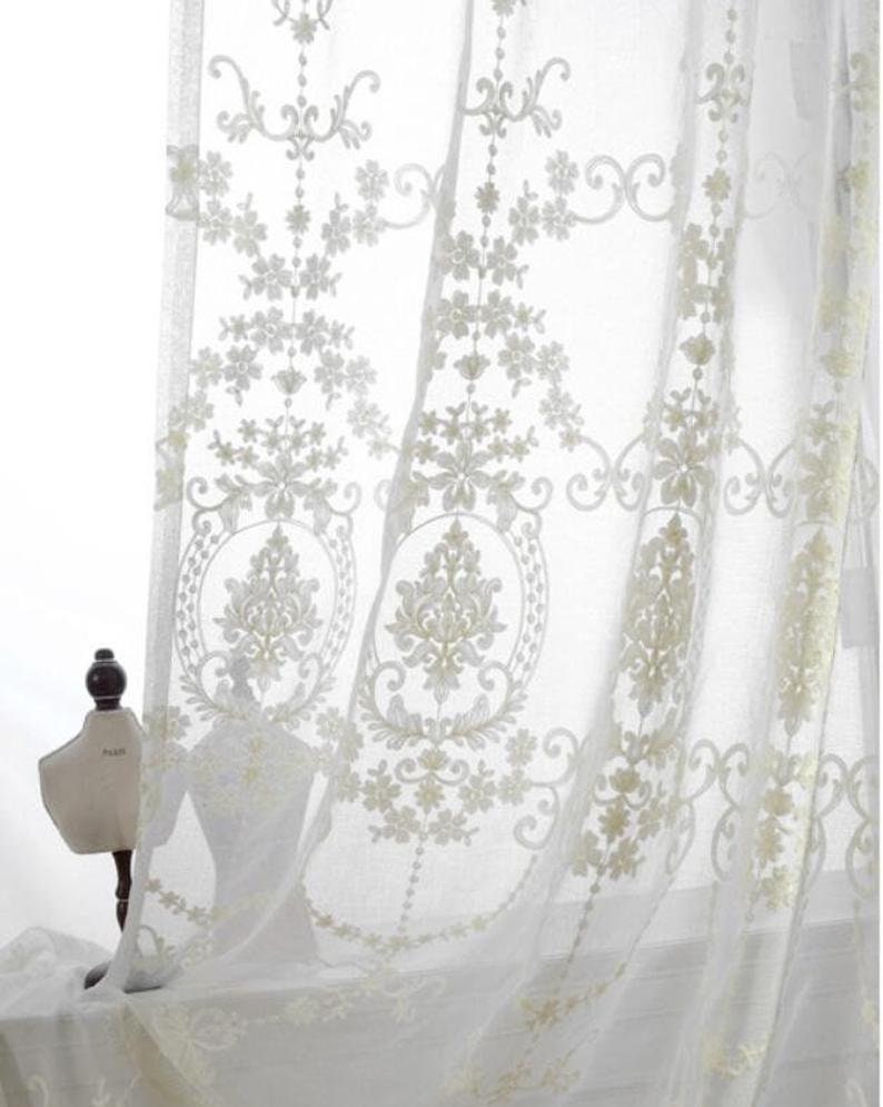 May include: White sheer curtains with an embroidered floral pattern. The curtains are made of a delicate fabric and have a romantic, vintage feel.