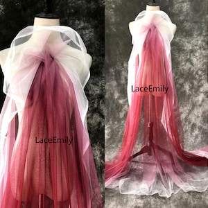 Peut inclure: Un tissu de tulle dégradé dans les tons de blanc, rose et rouge. Le tissu est drapé sur un mannequin et porte l'inscription "LaceEmily".