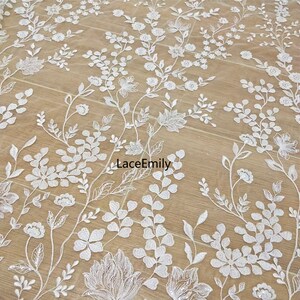 Pu&ograve; includere: Tessuto di pizzo floreale bianco con un delicato motivo di fiori e foglie. Il tessuto &egrave; leggero e trasparente, perfetto per creare abiti, accessori o decorazioni per la casa.