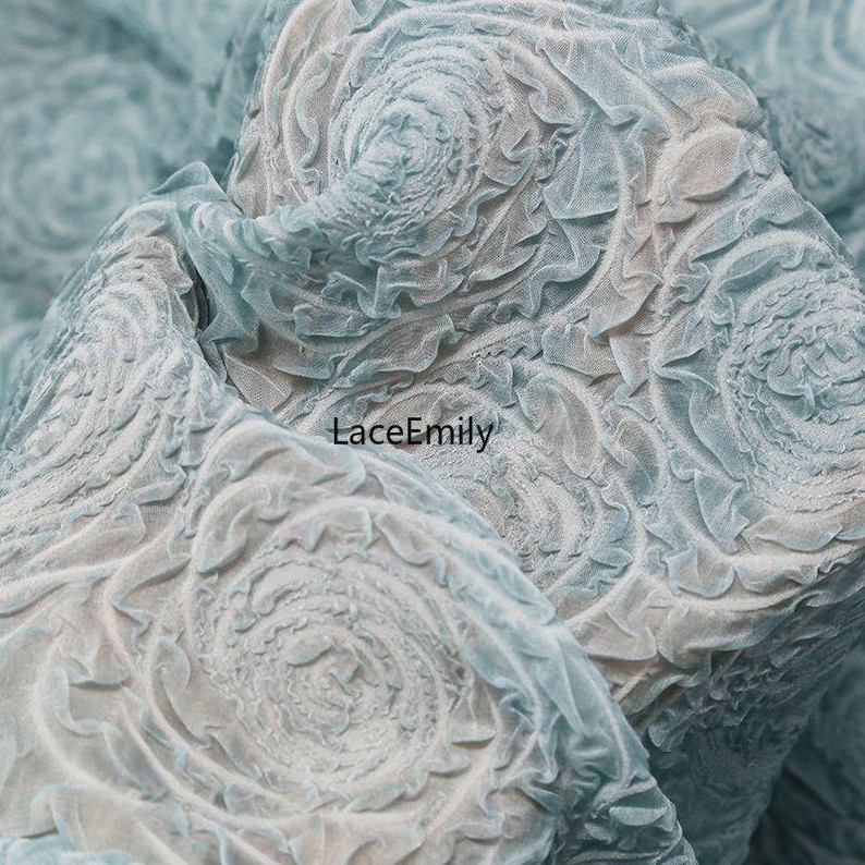 Puede incluir: Primer plano de una tela azul claro con un patr&oacute;n floral arremolinado texturizado. La tela tiene un efecto en capas y tridimensional, con el texto "LaceEmily" visible en el centro inferior.