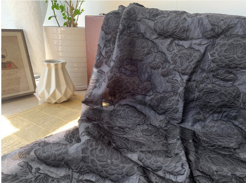 Puede incluir: Tela negra transparente con un patr&oacute;n floral en relieve. La tela tiene una calidad delicada, casi transparente y presenta dise&ntilde;os florales en relieve.