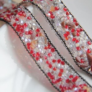 May include: Two strands of red and silver beaded trim with black thread running through the center. The trim is made of small, faceted beads and is perfect for adding a touch of sparkle to any project.