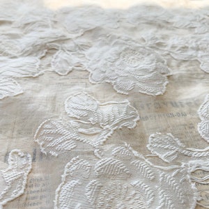 Puede incluir: Tela blanca bordada con un patr&oacute;n floral. La tela es transparente y delicada, con un dise&ntilde;o en relieve.