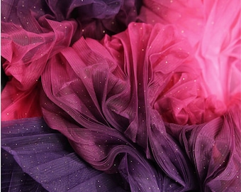 Peut inclure: Gros plan sur un tissu de tulle ombré rose et violet avec des paillettes dorées. Le tissu est froncé et plissé, créant une texture douce et délicate.