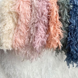 Puede incluir: Una colección de seis diferentes flecos de tela esponjosa en varios colores. Los flecos están dispuestos en una fila de izquierda a derecha. Los colores son blanco, crema, rosa claro, rosa, melocotón y azul.