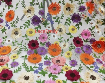 Puede incluir: Una tela blanca transparente con flores bordadas de colores. Las flores son en tonos de naranja, amarillo, rosa, morado y rojo. La tela es perfecta para proyectos de manualidades, costura y decoración del hogar.