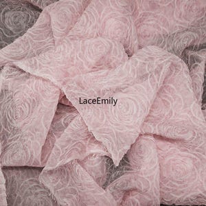 Puede incluir: Primer plano de una tela rosa suave con un patr&oacute;n de rosas. La tela est&aacute; en capas y tiene una apariencia delicada y texturizada. El texto "LaceEmily" es visible en la imagen.
