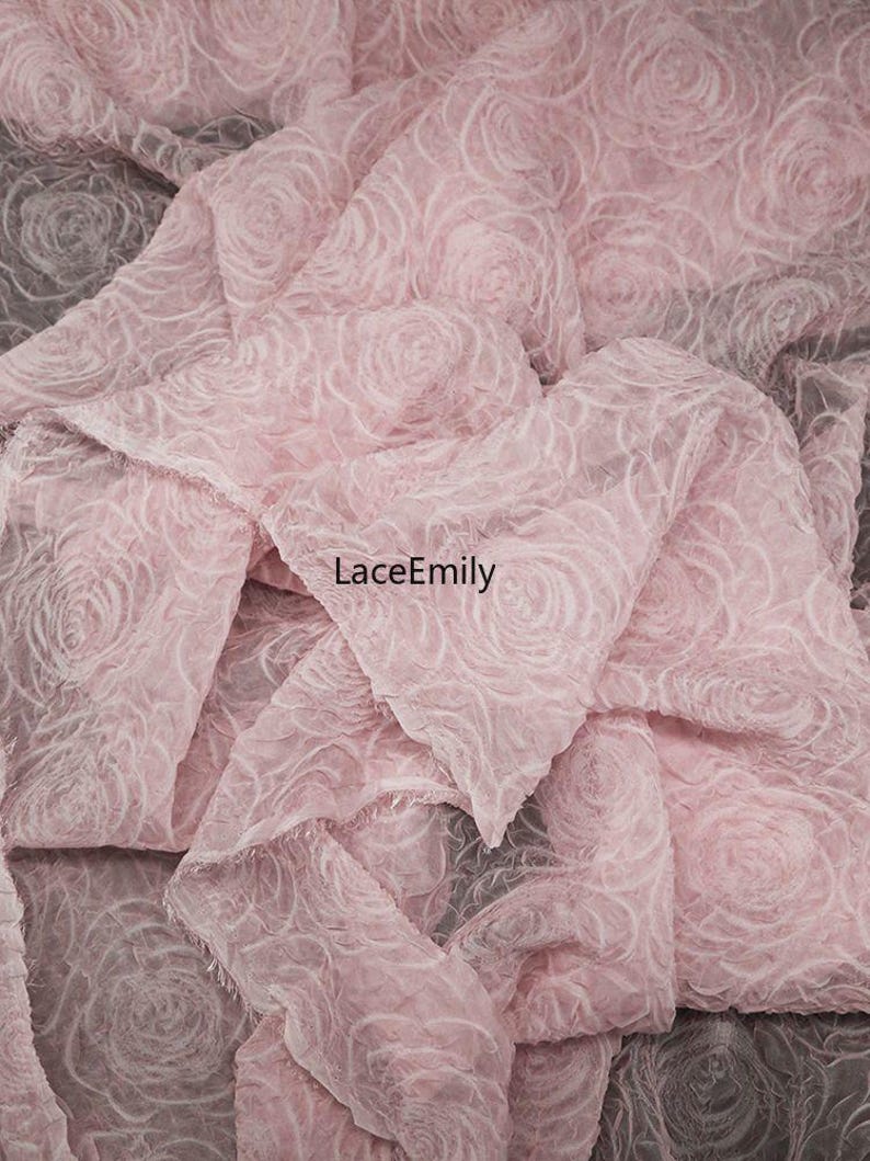 Puede incluir: Primer plano de una tela rosa suave con un patr&oacute;n de rosas. La tela est&aacute; en capas y tiene una apariencia delicada y texturizada. El texto "LaceEmily" es visible en la imagen.