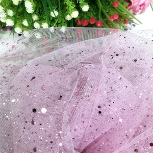 Könnte beinhalten: Rosa Tüllstoff mit silbernem Glitzer. Der Stoff ist durchsichtig und hat eine zarte Textur.