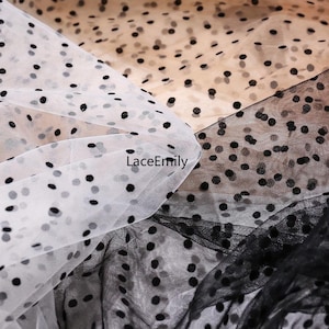 May include: Sheer tulle fabric in beige, white, and black, each featuring a repeating pattern of small black polka dots. The fabric is layered, showing the translucent quality of the material. The text LaceEmily is printed on the white fabric.