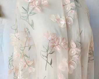 Puede incluir: Tela de tul de color marfil transparente con bordado floral rosa pálido. El diseño floral presenta flores y hojas delicadas.