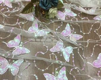 May include: White sheer fabric with iridescent purple butterfly sequins. The fabric is delicate and has a soft, flowing texture.