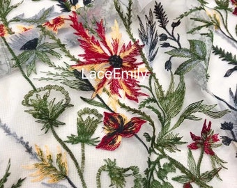 May include: Red, yellow and green embroidered floral pattern on a white sheer fabric. The fabric has a delicate, lace-like texture.