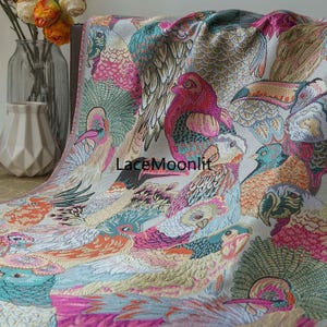 Puede incluir: Un textil colorido con un patrón repetido de aves estilizadas en tonos de rosa, turquesa, naranja y dorado. Las aves se destacan sobre un fondo gris claro. El texto "LaceMoonlit" es visible en la tela.