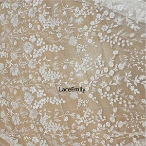 Pu&ograve; includere: Tessuto di pizzo floreale bianco con un delicato motivo di fiori e foglie. Il tessuto &egrave; trasparente e ha una texture morbida e fluida. Il testo "LaceEmily" &egrave; visibile al centro dell'immagine.