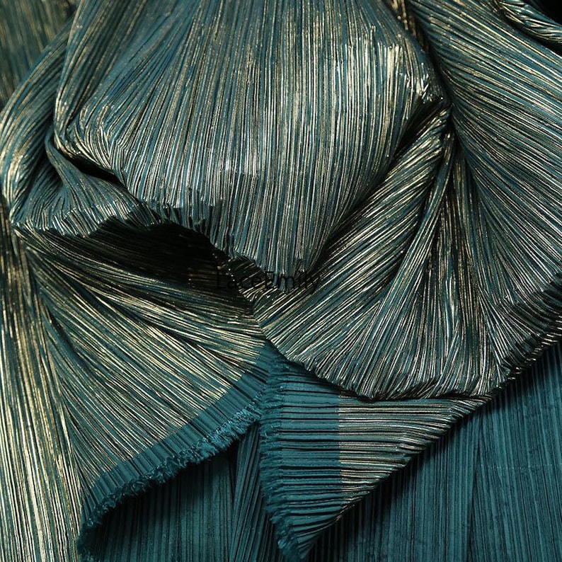 May include: Close-up of teal fabric with vertical pleats and a metallic gold sheen. The fabric is gathered and folded, creating a textured and layered effect. The material has a luxurious appearance, suitable for apparel or decorative projects.