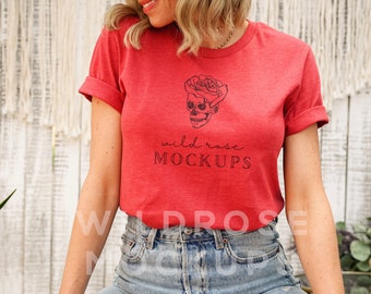 以下が含まれることがあります： 「wild rose MOCKUPS」というテキストと、骸骨とバラのグラフィックが描かれた赤いTシャツです。