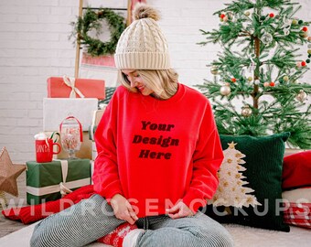 May include: A red sweatshirt with the text "Your Design Here" in black. The sweatshirt is being worn by a person sitting on a white rug with a Christmas tree and presents in the background.