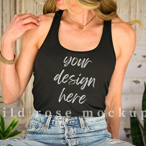 May include: A black racerback tank top with the text "your design here" printed on the front. The model is wearing the tank top with blue denim jeans.
