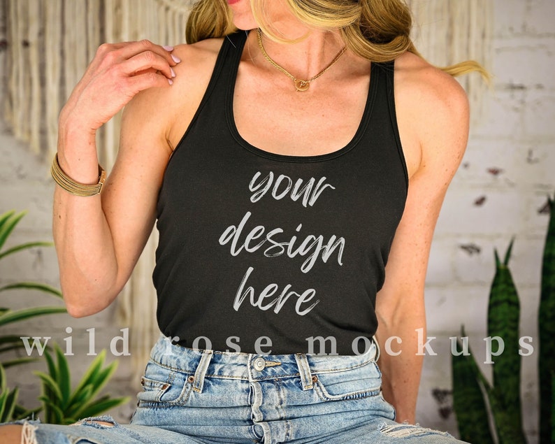 May include: A black racerback tank top with the text "your design here" printed on the front. The model is wearing the tank top with blue denim jeans.