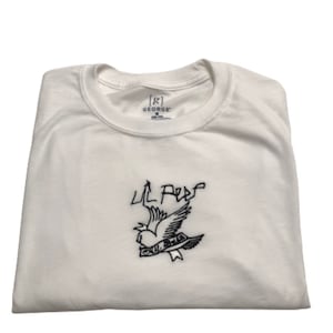 May include: White t-shirt with a black embroidered design of a bird with the text "Lil Peep" above it.