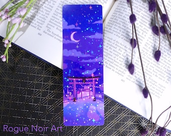 May include: A holographic bookmark depicting a purple and blue night sky with a crescent moon, stars, and a traditional Japanese red torii gate. The gate is surrounded by trees and a path leading to it. The bookmark has a glittery finish.