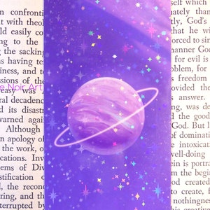 May include: A purple planet with a ring around it, surrounded by a purple and blue galaxy with white stars. The planet has a light purple and white swirl pattern.