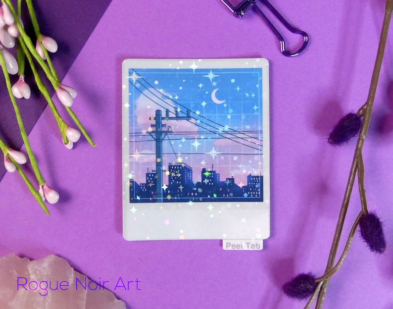 Puede incluir: Una pegatina que representa una ciudad nocturna con una luna creciente y estrellas. La pegatina tiene un acabado hologr&aacute;fico con un efecto brillante. La pegatina tiene una pesta&ntilde;a de despegue que dice "Peel Tab".