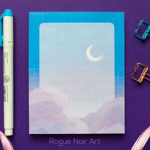 May include: A blue and white gridded notecard with a crescent moon and clouds in a pastel blue and purple colour scheme. The text "Rogue Noir Art" is printed at the bottom of the card.