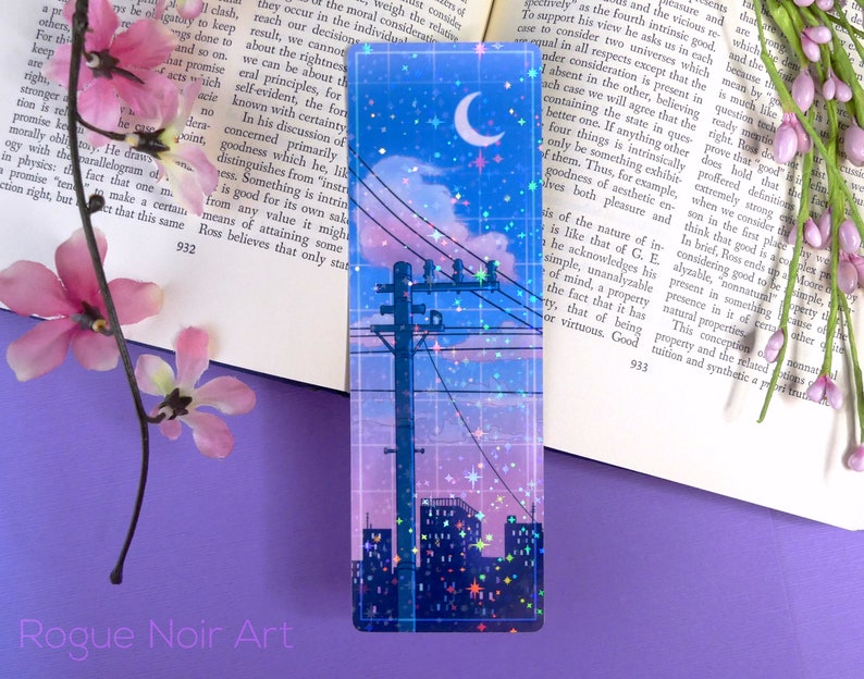 May include: A blue and pink city skyline with a crescent moon and stars. The image is a holographic bookmark with a grid pattern and glitter accents.