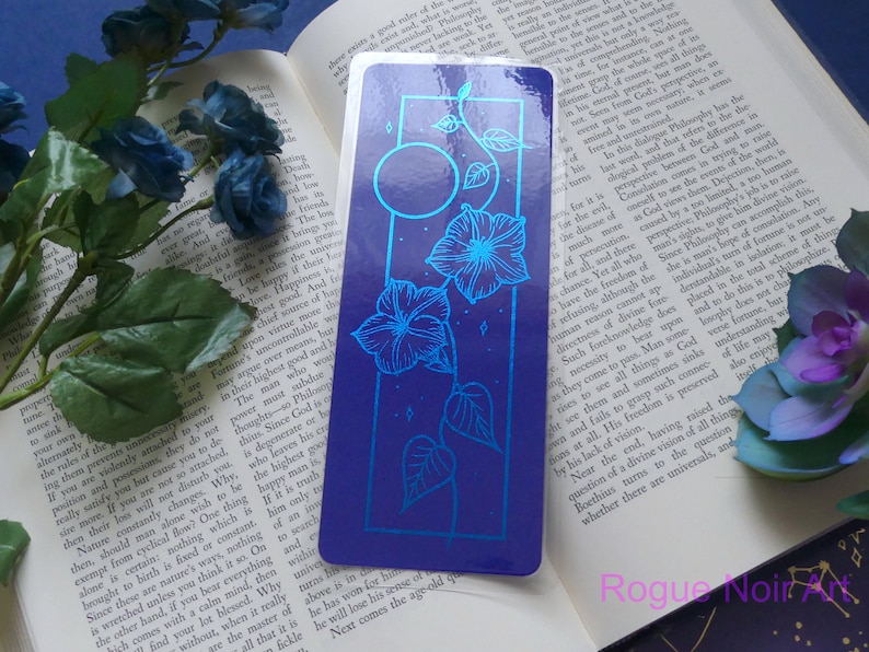 May include: A blue and silver bookmark with a floral design and a moon. The bookmark has a blue background with silver flowers and a moon. The bookmark is a great way to mark your place in a book.