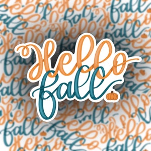 May include: A sticker with the text "hello fall" in orange and blue lettering with a small orange pumpkin graphic. The background is a blurred pattern of the same text in orange and blue.