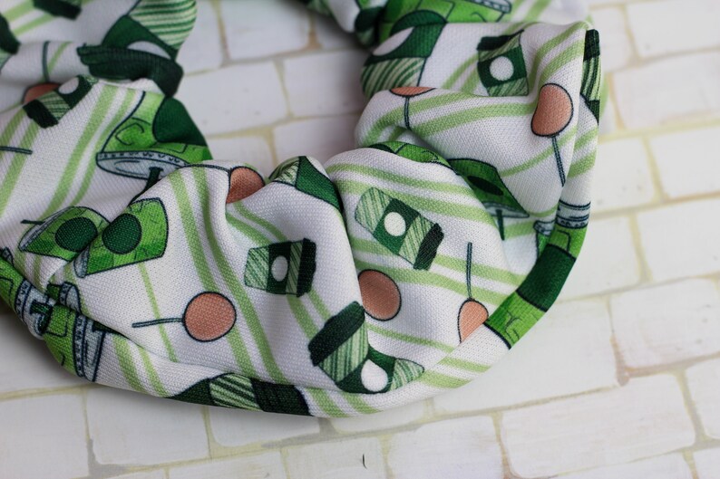 Op de afbeelding: Een witte scrunchie met een groen-wit gestreept patroon. De scrunchie heeft een herhalend patroon van groene koffiebekers en groen-wit gestreepte lolly's.