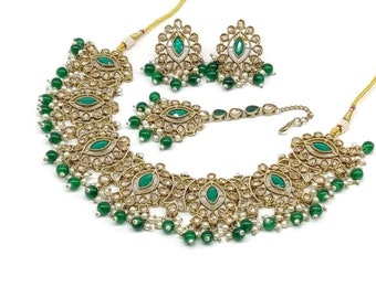 May include: A gold necklace set with green and white stones. The necklace has a layered design with a pendant and matching earrings.