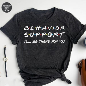 May include: Heather dark grey t-shirt with the text "BEHAVIOR SUPPORT I'LL BE THERE FOR YOU" in white. The text is styled to look like the font used in the TV show "Friends".
