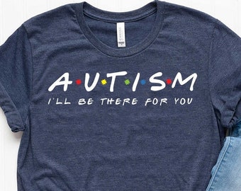 Puede incluir: Una camiseta azul marino con texto blanco que dice "A*U*T*I*S*M I'LL BE THERE FOR YOU". La camiseta está sobre una superficie blanca con un par de zapatillas blancas y unos vaqueros azules.