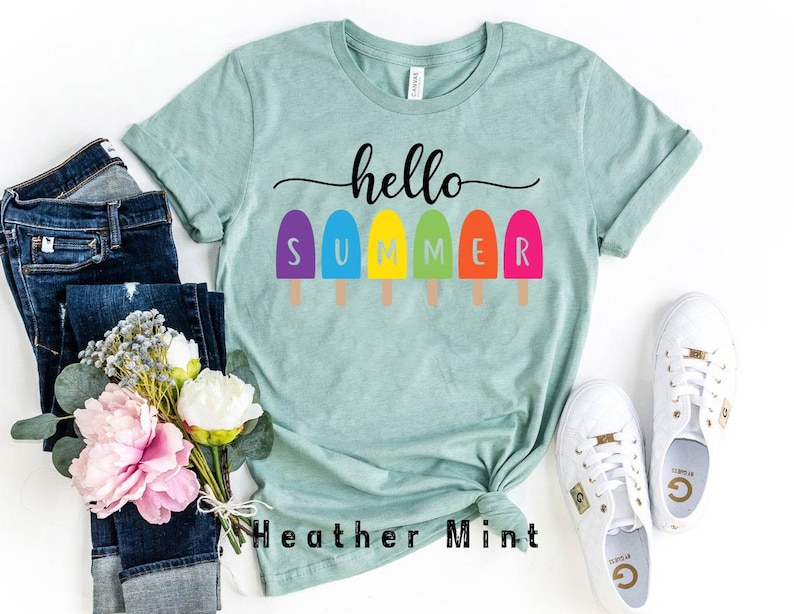 May include: A light green t-shirt with the words "hello SUMMER" and colorful popsicle graphics. The shirt is paired with blue jeans, white sneakers, and a bouquet of pink and white flowers. The text "Heather Mint" is also visible.